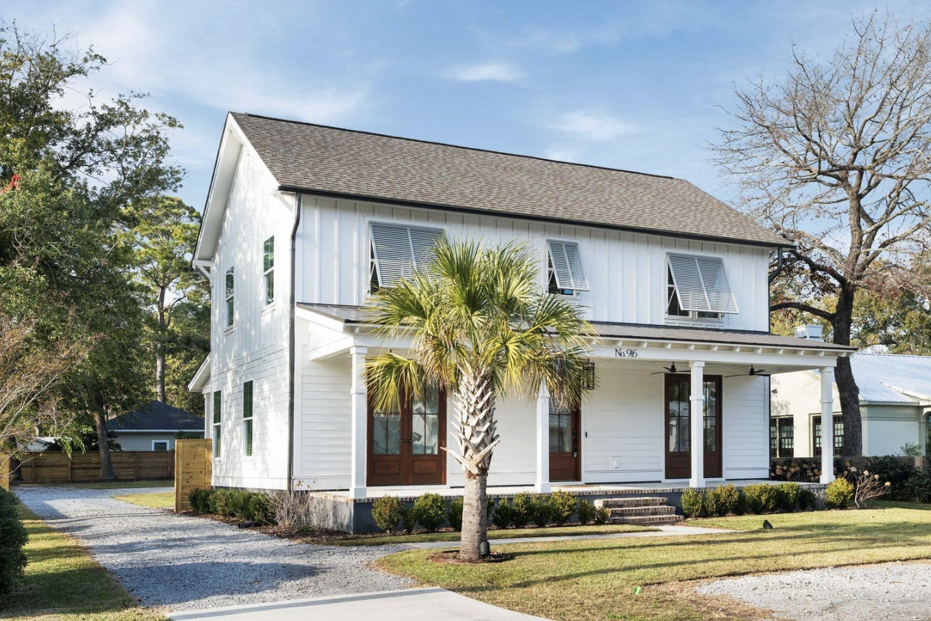 White board-and-batten two-story home with palmetto and front porch at 916 Kincade Drive